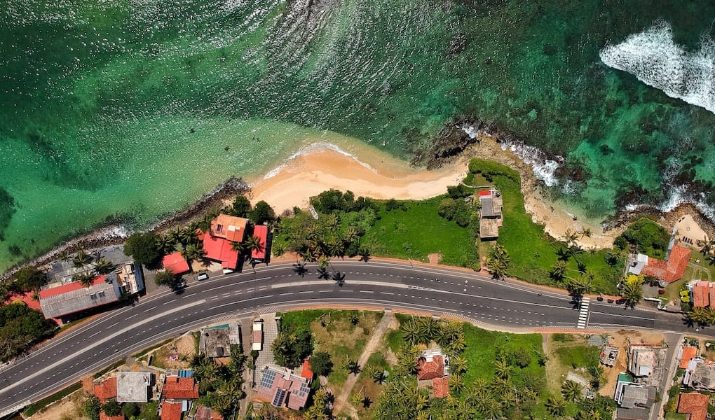 Coastal road in Sri Lanka with blue-green ocean running alongside